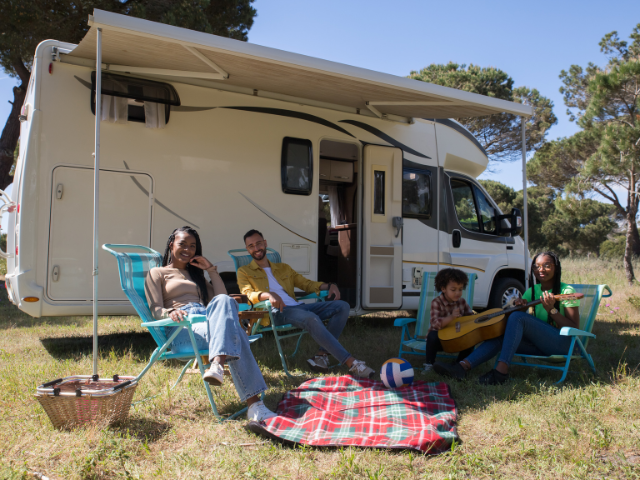 A group of people sitting in chairs outside of a RV at Avila Beach camping. RV Lifestyle Experts