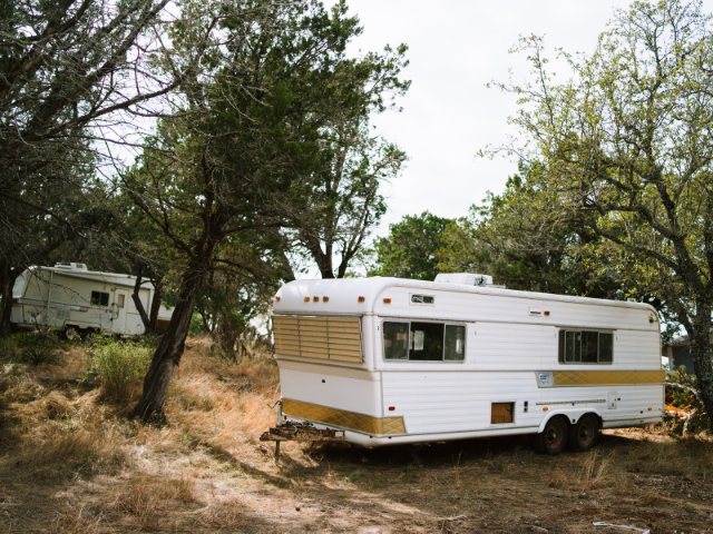 Two RV trailers parked in a wooded area on Angel Island camping grounds. RV Lifestyle Experts