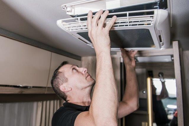 A man repairing a solar-powered RV air conditioner. RV Lifestyle Experts