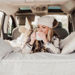 Unlock The Ultimate Guide To Solar Power Heater For RV A woman sitting in the back seat of a van with a cup of coffee, enjoying the solar power heater for RV. RV Lifestyle Experts