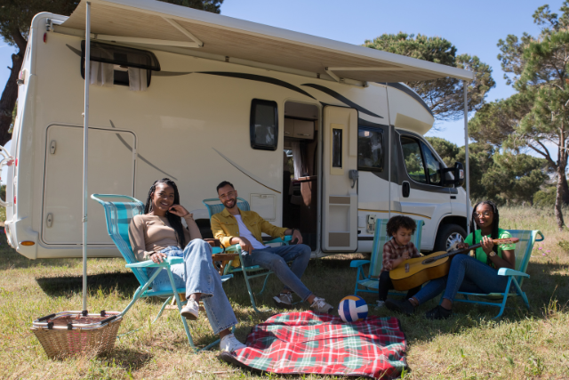A group of people sitting in chairs outside of a RV at Avila Beach camping. RV Lifestyle Experts