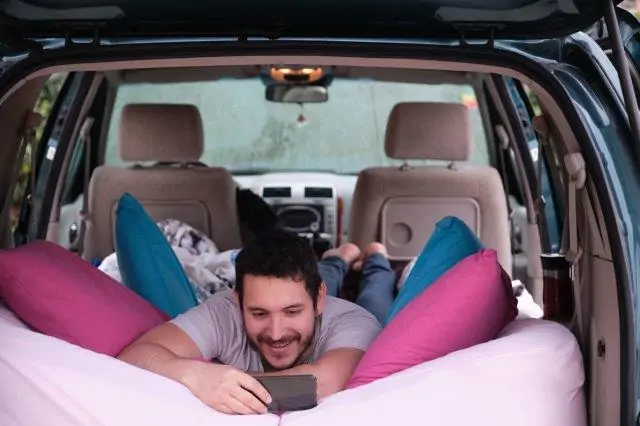 A man lying in the back seat of a car with pillows. RV Lifestyle Experts
