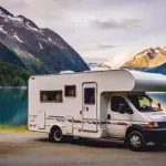 A white RV parked in front of a lake, staying cool in extreme heat. RV Lifestyle Experts