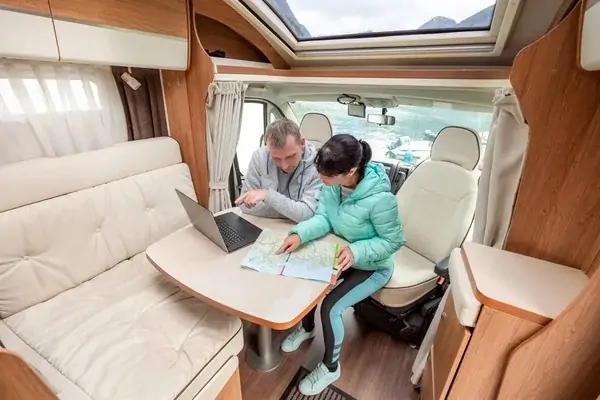 Two people sitting in an rv with a laptop on the table. RV Lifestyle Experts