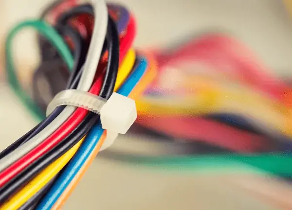 A bundle of multicolored wires secured with a white cable tie, with blurred colorful background. RV Lifestyle Experts