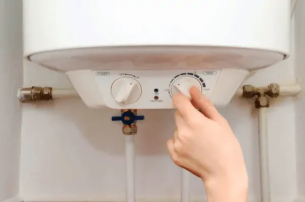 A person adjusting the temperature setting on an electric water heater. RV Lifestyle Experts